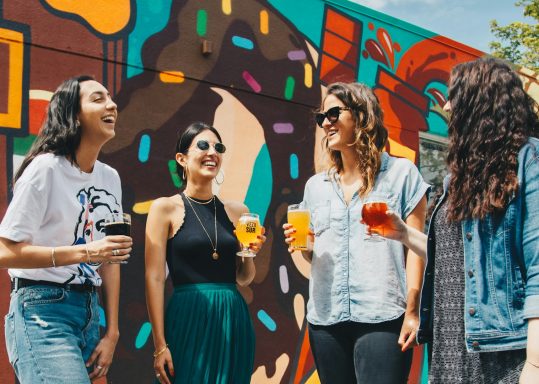 Verbindung vier Frauen stehen und lächeln und prosten sich zu